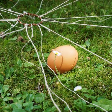 Ein rohes Ei in der Wiese mit Schnüren für ein Spiel